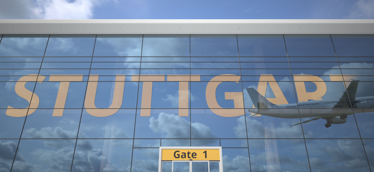 Foto startendes Flugzeug, das sich im Schaufenster einer großen Halle mit der Aufschrift "Stuttgart spiegelt.
